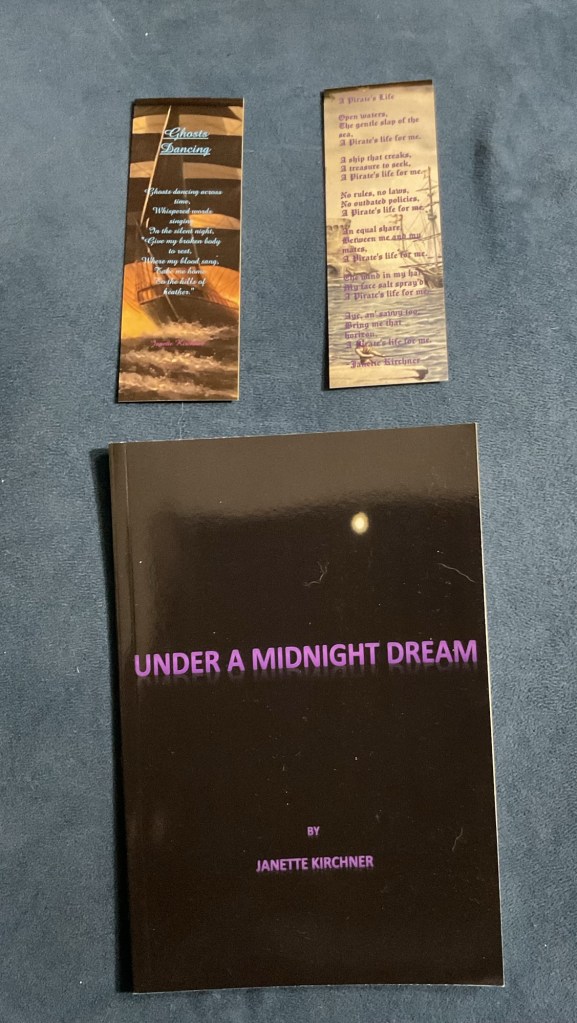Picture of a book titled Under A Midnight Dream, and 2 bookmarks. The bookmark on the left is of the poem Ghosts Dancing and the bookmark on the right is the poem A Pirate's Life. They are situated above the book.